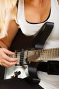 Woman playing on electric guitar, black background