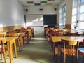 Music solfeggio empty class at school. The sun's rays fall on the floor through the window. Wooden student tables