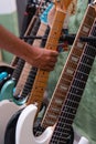 Music stand with many guitars and a hand taking one.