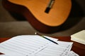 Music staves and a notebook on the table in front of a classical guitar Royalty Free Stock Photo