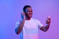 Music Streaming App. Black Guy Listening Favorite Songs On Smartphone, Neon Light Royalty Free Stock Photo