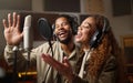Music, streaming and black couple recording in studio, singing into microphone with headphones and radio. Technology