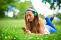 Music is the sweetest escape...a young woman listening to music while lying on the grass at the park.