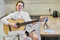 A music teacher gives a quarantine guitar lesson. Studying and hobbies in the coronavirus epidemic. Woman sitting with a guitar in