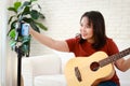 Music teacher plays guitar online live via smartphone.