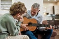 Music time. Mature caucasian man grandfather playing guitar to his little grandson, teaching new musical instrument Royalty Free Stock Photo