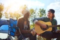 Music is a way to express your feelings. a young man playing his girlfriend a song on his guitar while out camping. Royalty Free Stock Photo