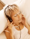 Music - Woman in living room listening to MP3 player smiling Royalty Free Stock Photo