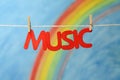 The word music with a colorful rainbow and blue sky background