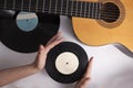 Musical background, guitar and old vinyl records in female hands. Royalty Free Stock Photo