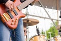 Musical band perfom on an open air festival. Bass guitarist man playing close, drums blurry Royalty Free Stock Photo