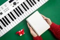 Musical Christmas background with keys and blank notepad in female hands, flat lay.