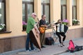 A musical group of three people on an old European street. The band consists of two men and one girl. Men with a double bass and a