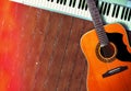 Musical instrument - MIDI keyboard and vintage acoustic guitar wood background Royalty Free Stock Photo