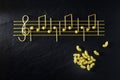 Musical Italian pasta in the form of notes, isolated on a black textural background Royalty Free Stock Photo