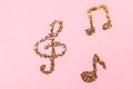 Musical notes of starry golden confetti lying on a pink pastel background.