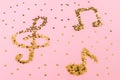 Musical notes of starry golden confetti lying on a pink pastel background.