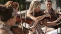 Musical quartet. Three violinists and cellist playing music. Close up.