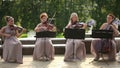 Musical quartet. Three violinists and cellist playing music. Long shot.