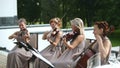 Musical quartet. Three violinists and cellist playing music. Medium shot.