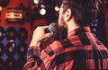 Musician with beard singing song in karaoke, rear view. Rock singer concept. Guy likes to sing in dark karaoke hall. Man Royalty Free Stock Photo