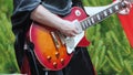 A musician in black gothic clothes plays the electric guitar.