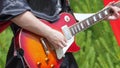 A musician in black gothic clothes plays the electric guitar.