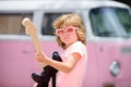 Musician child with a guitar. Joyful cute kid improvising. Happy kid enjoys music over colorful pink background.