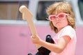 Musician child with a guitar. Joyful cute kid improvising. Happy kid enjoys music over colorful pink background.