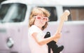 Musician child with a guitar. Joyful cute kid improvising. Happy kid enjoys music over colorful pink background.