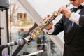 A musician at the event in a frock coat and bow tie plays the saxophone. ÃÂ¡lose-up of hands and tools.