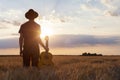 Musician holding acoustic guitar and walking in summer fields, sunset Royalty Free Stock Photo