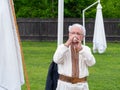 Musician man plying conch, conchor, conque, seashell horn or shell trumpet from sea snail ethnic wind musical instrument