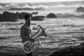 A musician man with a tuba on the Atlantic seashore. Black and white photo. Royalty Free Stock Photo