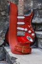 The musician places his red Fender Squier Stratocaster on the steps of the old building. A beautiful strap for a guitar. Royalty Free Stock Photo