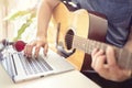 Musician playing acoustic guitar and recording music on computer