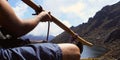 Man playing bamboo instrument with lagoon background