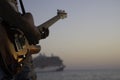 Musician playing electric guitar at sunset, cruise ship in the background. Royalty Free Stock Photo