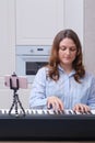 Musician playing melody on digital piano and phone on tripod