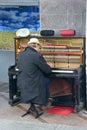 Musician playing piano outdoors. Pianist earning living by playing with piano