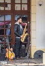 The musician playing the saxophone performs on the street in front of The State Philharmonics Sibiu - Thalia Concert Hall. Sibiu c