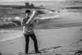 A musician playing a tuba on the ocean. Black and white photo. Royalty Free Stock Photo