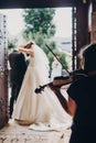 Musician playing on violin while beautiful bride and groom standing in church after wedding matrimony. Elegant string quartet Royalty Free Stock Photo