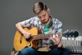 A musician plays an acoustic guitar in a checkered shirt. bearded