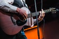 The musician plays the acoustic guitar on stage. Guitar neck close-up on a concert of rock music in the hands of a musician.