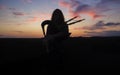 A musician plays the bagpipes in the fields at sunset