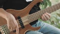 The musician plays a five-string bass guitar with his fingers on the street in the summer