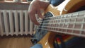 The musician plays a five-string bass guitar at home