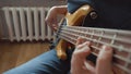 The musician plays a five-string bass guitar at home