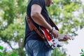 A musician plays a red Fender Squier Stratocaster electric guitar and stands on an old brick wall. Royalty Free Stock Photo